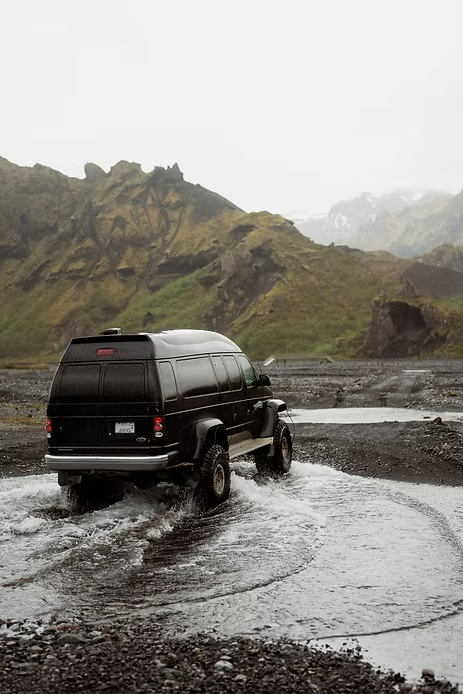 iceland wedding photographer takes a photo of 4x4 van going through river in valley.