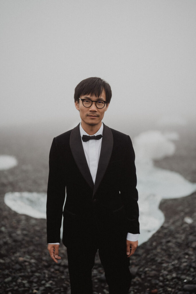 groom poses for iceland wedding photographer on diamond beach.