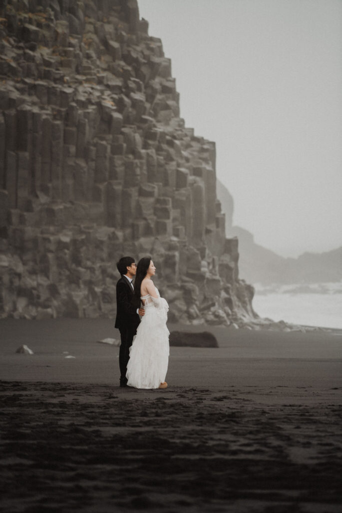 newlywed couple stands on iceland coast during adventure wedding photo shoot.
