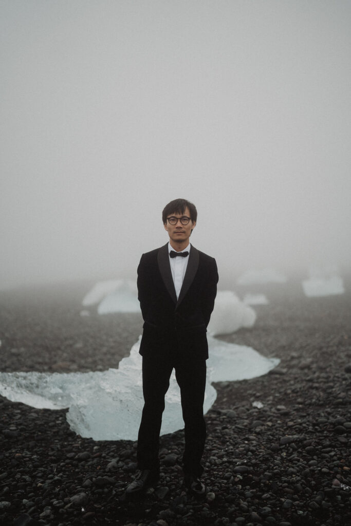 groom stands on diamond beach during iceland elopement