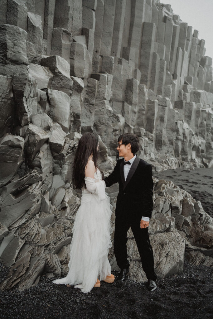 newlywed couple stands on rock formation during iceland wedding with wedding photographer.