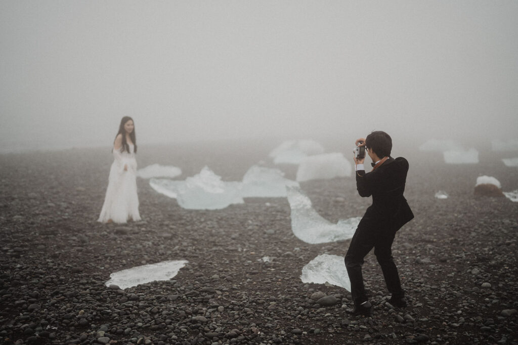 groom takes photo of bride during iceland elopement photo shoot.
