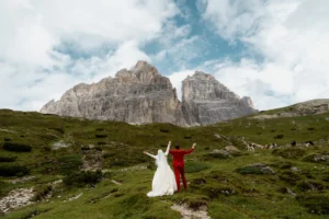 bride and groom look at mountains and put hands in the air during dolomites elopement in italy