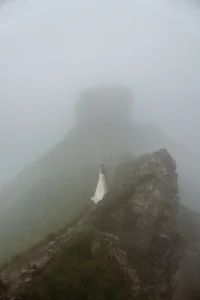 bride and groom stand on foggy rocky mountain during dolomites wedding photos