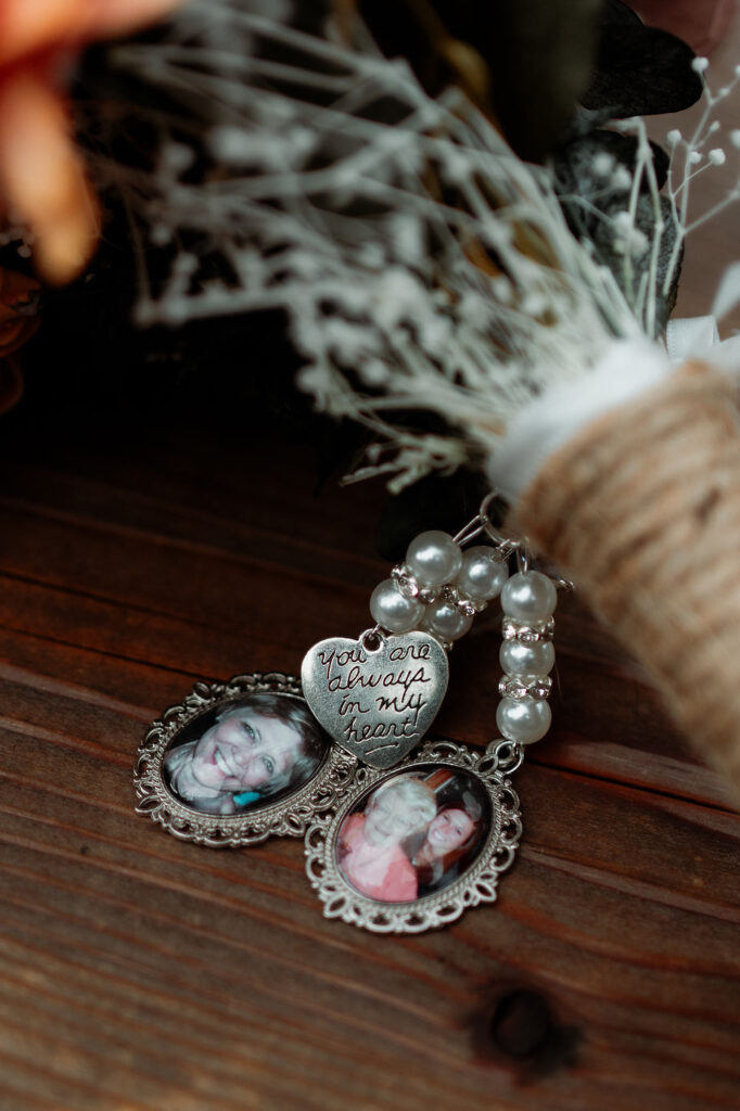 wedding bouquet with photo charms and pearl beads on a wooden surface. Heart charm reads "You are always in my heart," 