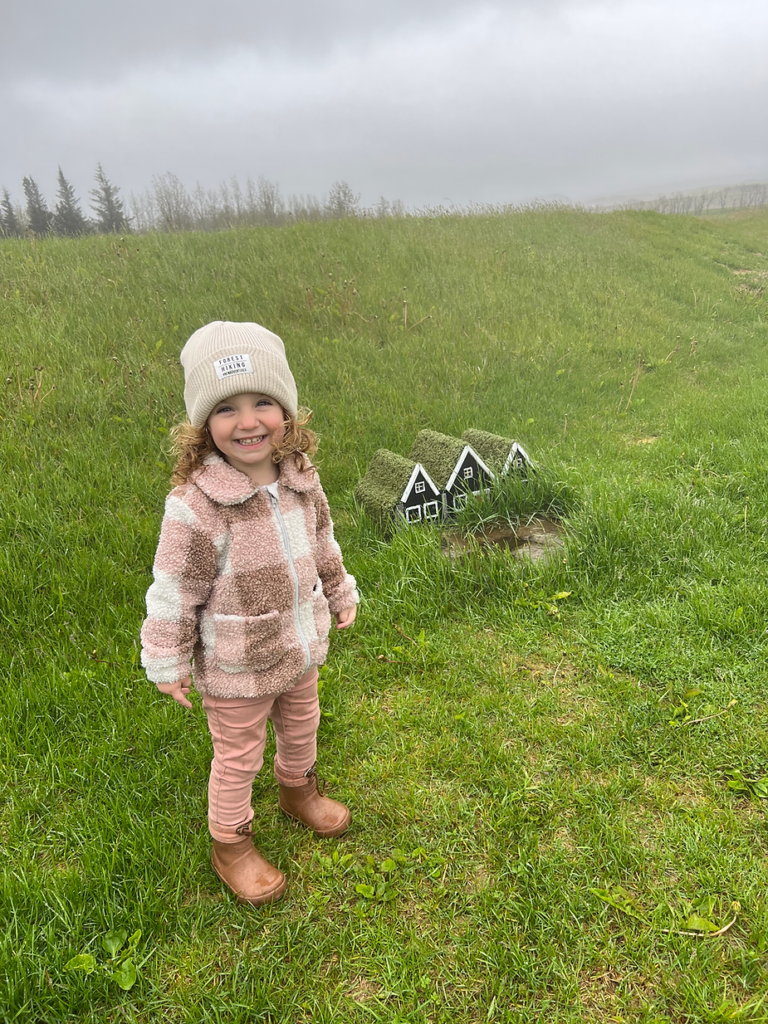 small child stands next to elf houses in iceland