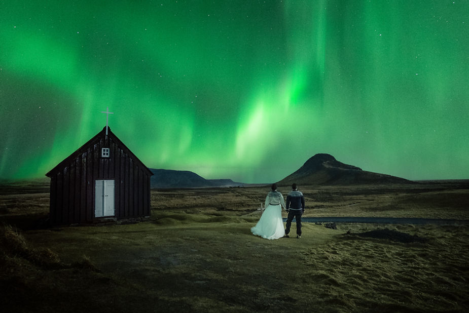 Krýsuvíkurkirkja, a church near geothermal fields, wiht northern lights surrounded by mist and mossy hills