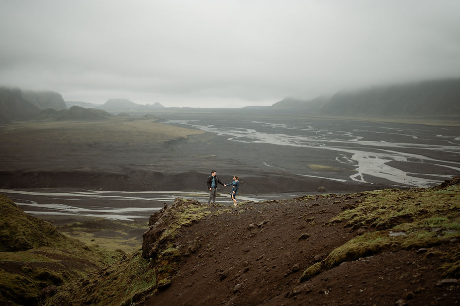 engaged couple stands on ledge and poses for iceland elopement photographer during surprise proposal pictures.