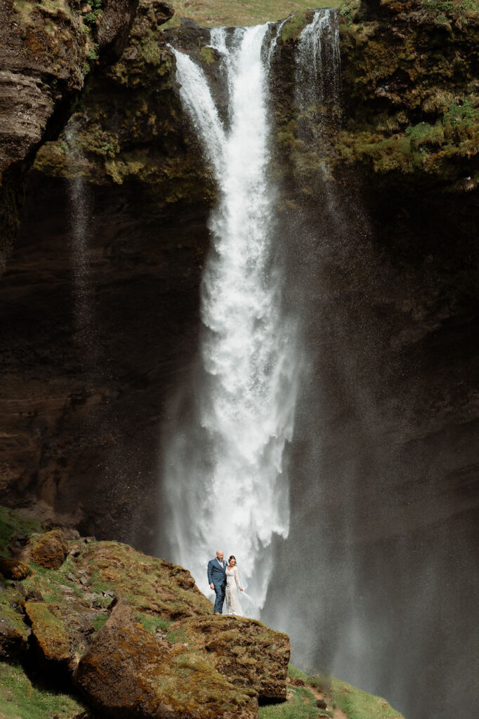 Bride and groom at the bottom of a waterfall during iceland adventure wedding in the westman islands.