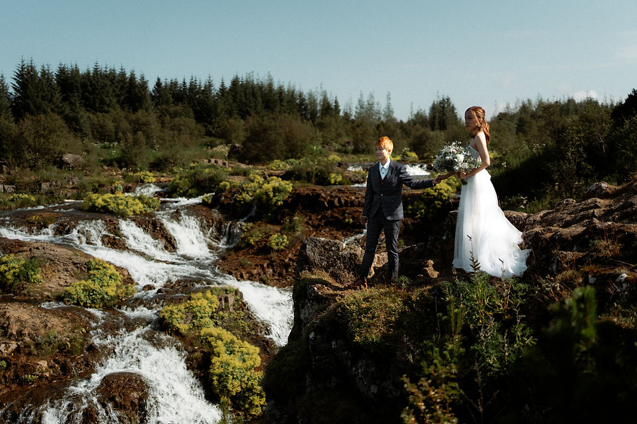two partners hold hands in lush green area during reykjavik iceland wedding photos.