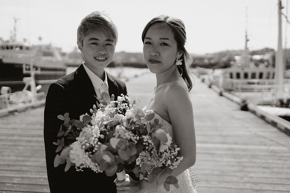 lgbtqi+ couple stand on reykjavik harbour during their destination wedding photos in iceland.