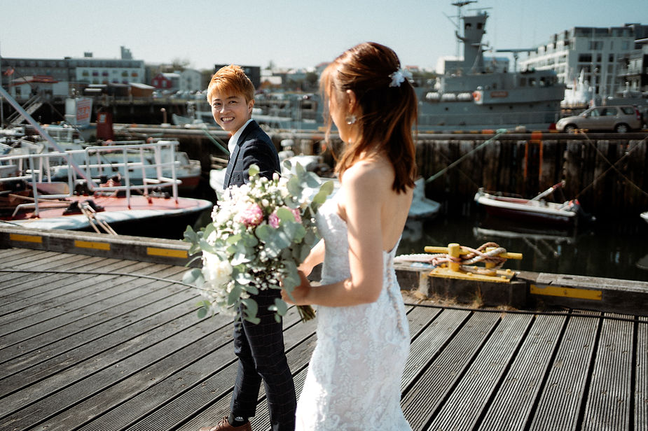 lgbtqi+ couple hold hands and walk down reykjavik harbour during iceland elopement photos.