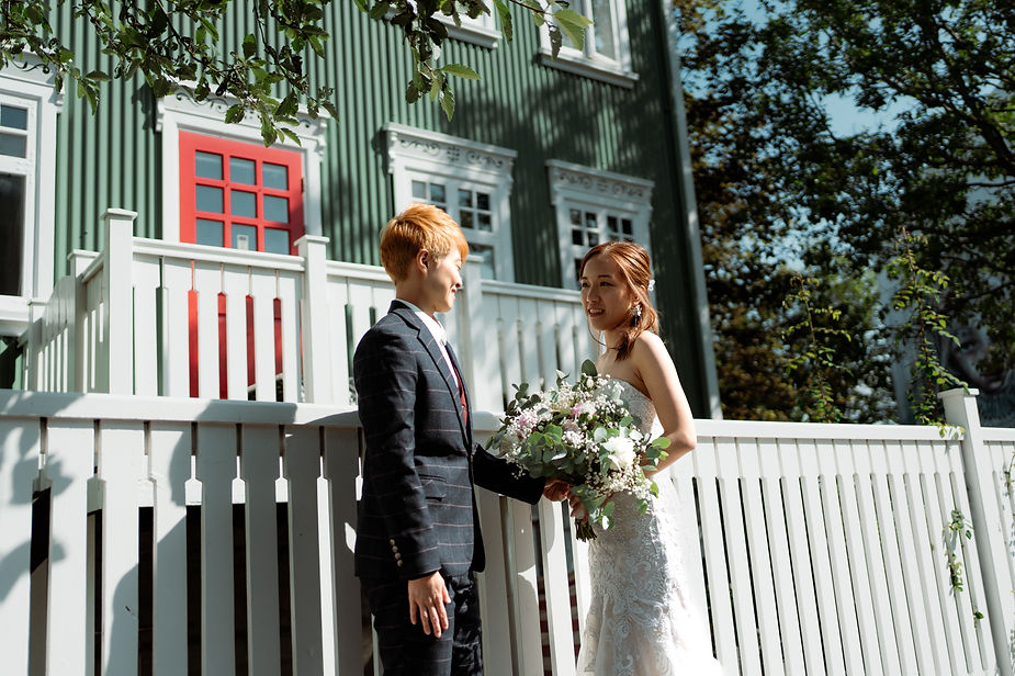 lgbtqi+ couple stands in front of green house in downtown reykjavik during their destination iceland wedding.