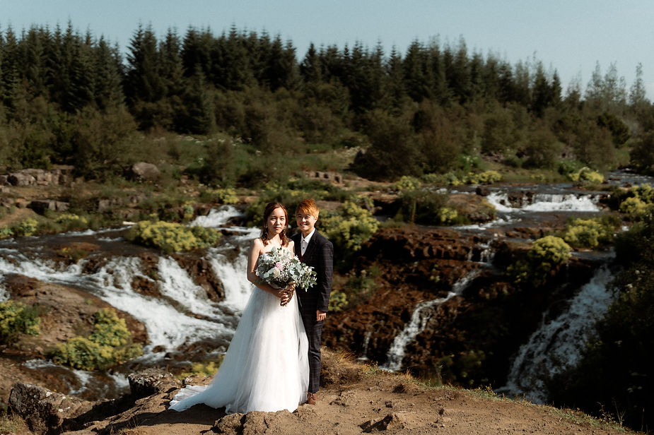 lgbtqi+ couple stands in front of lush green are in reykjavik during their destination wedding in iceland.