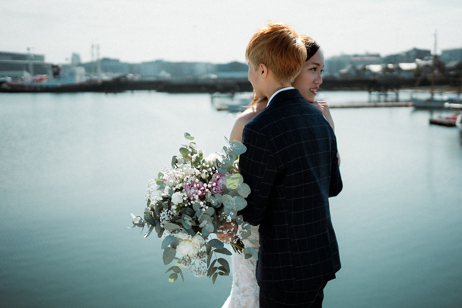 lgbtqi+ couple hugs on reykjavik harbour during destination wedding photos in iceland.