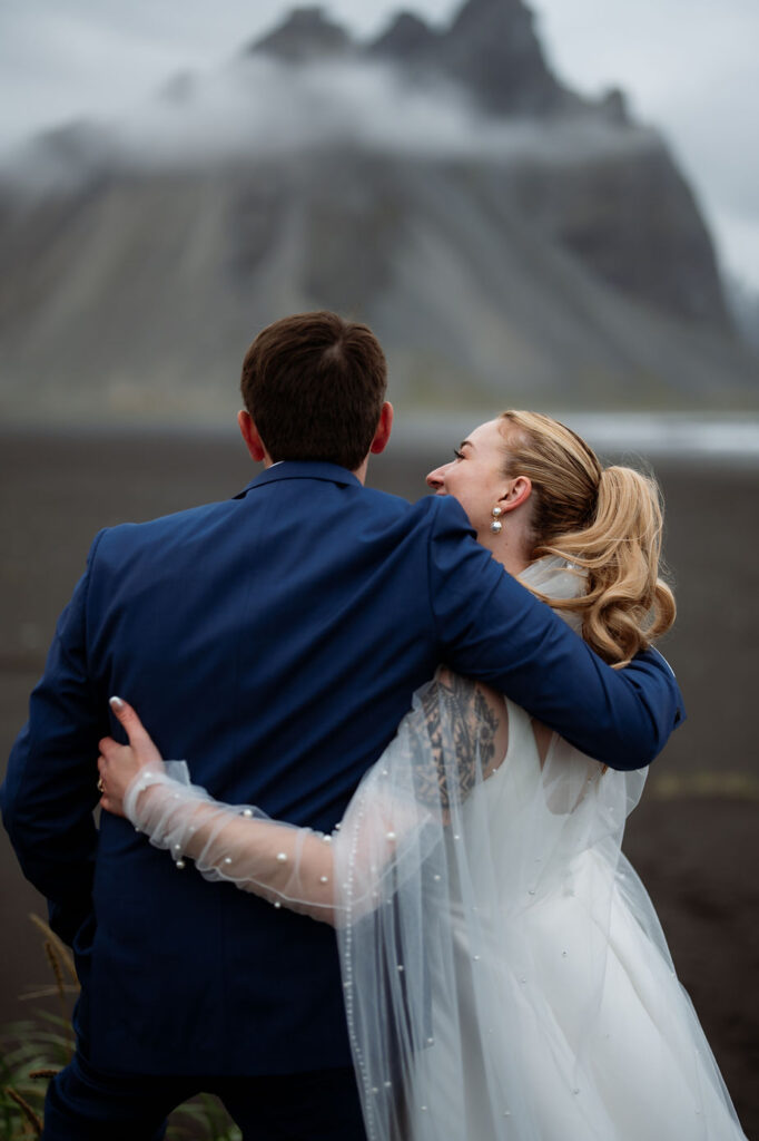 bride and groom embrace and smile during iceland wedding day adventure.
