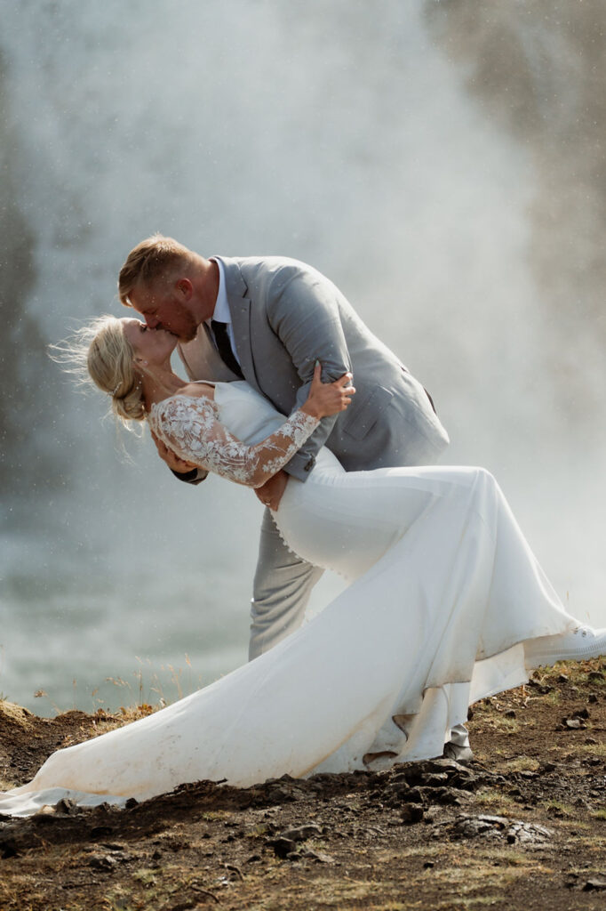 groom dips bride and kisses her during iceland wedding photos.