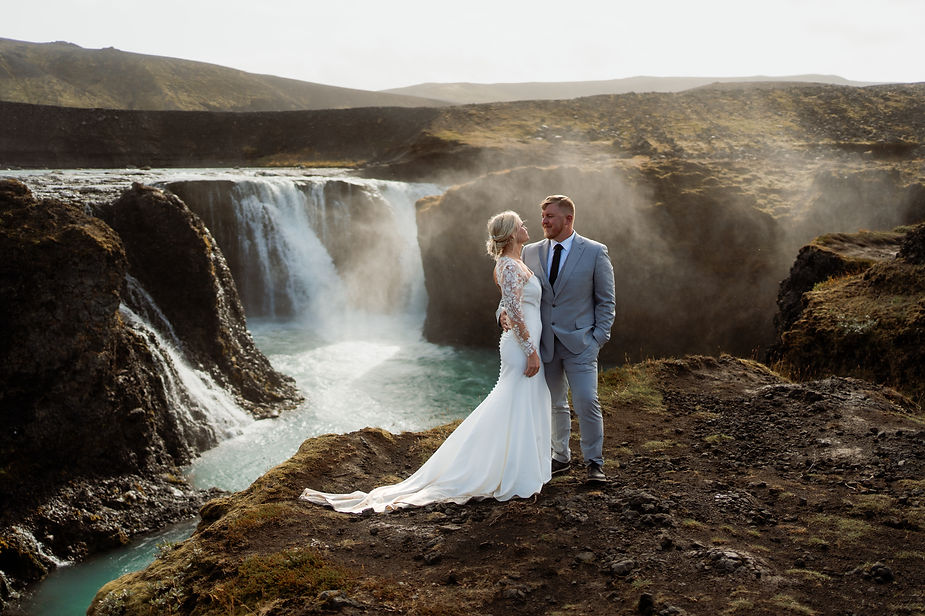 bride and groom stand in front of waterfall in iceland during elopement day.